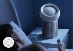 Woman in bed using her remote control to set her Dyson Pure Cool Me™ sleep timer